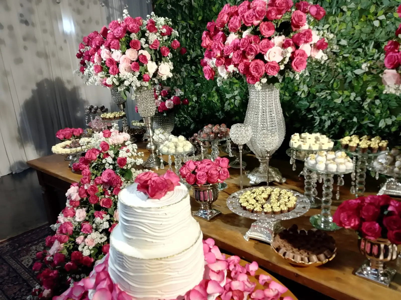 Mesa de bolo e doces decorada com rosas rosadas e peças de cristal