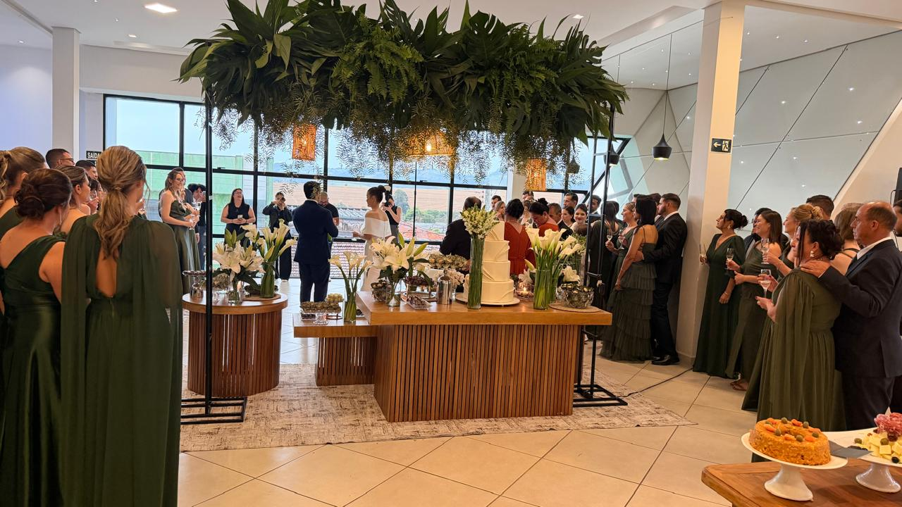 Recepção de casamento com jardim suspenso de folhagens sobre a mesa do bolo