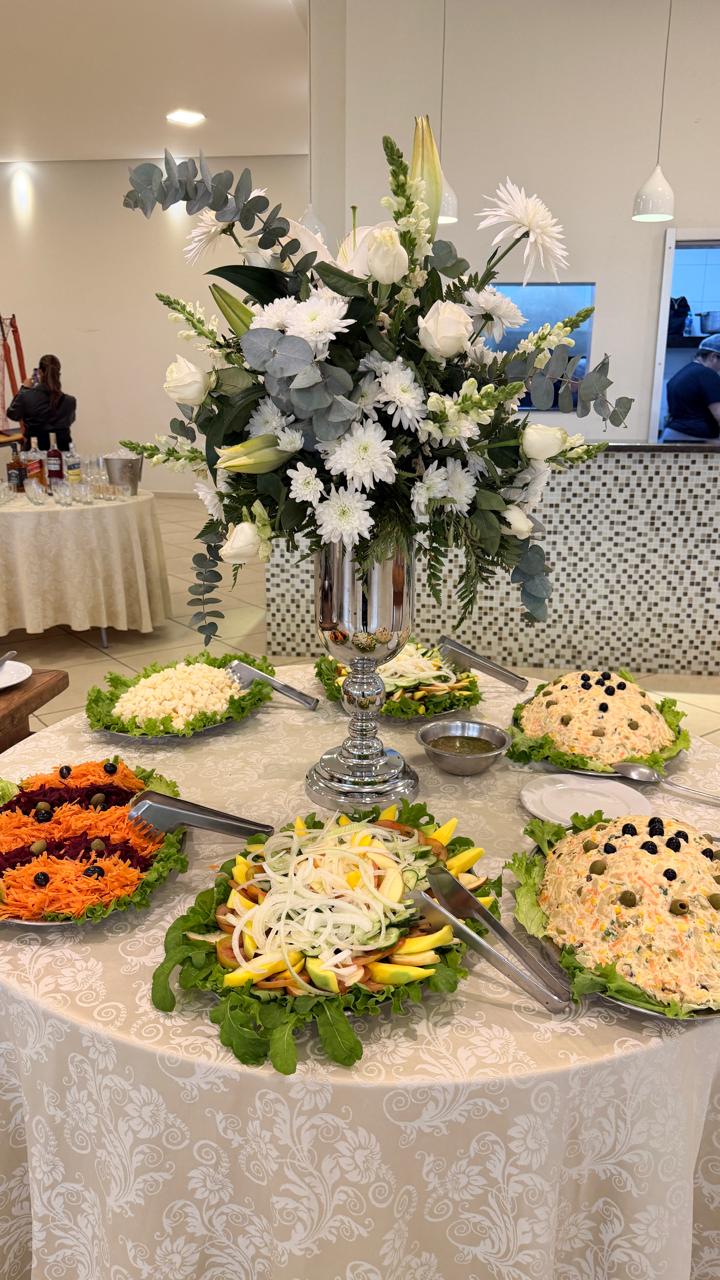 Mesa de saladas e maioneses com arranjo de flores brancas